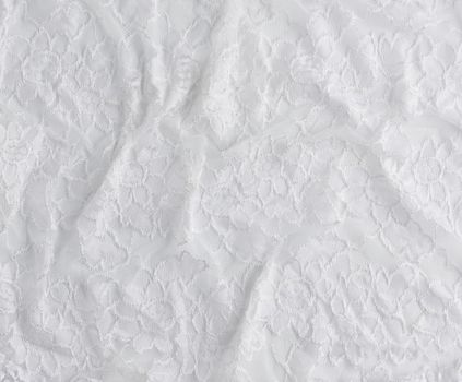 texture of crumpled white synthetic fabric guipure for sewing clothes on a white background, full frame