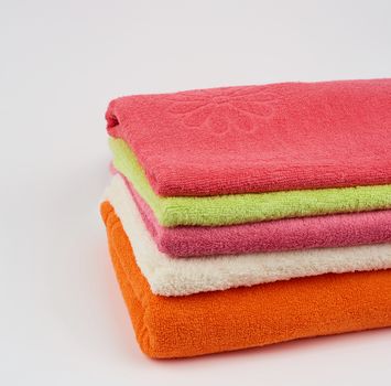 stack of colored cotton terry folded towels on a white background,  close up