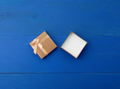 open brown square cardboard empty box, item lies on a blue wooden background, top view, copy space
