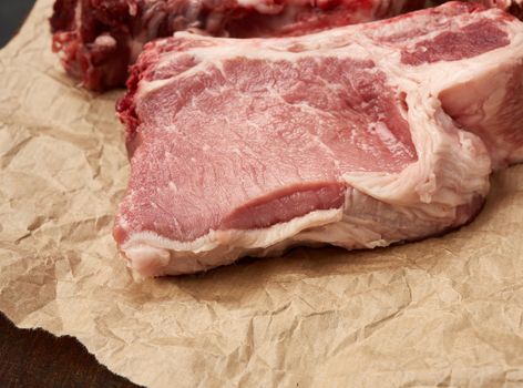 raw juicy pork slices of meat on the rib, food lies on brown parchment paper, top view