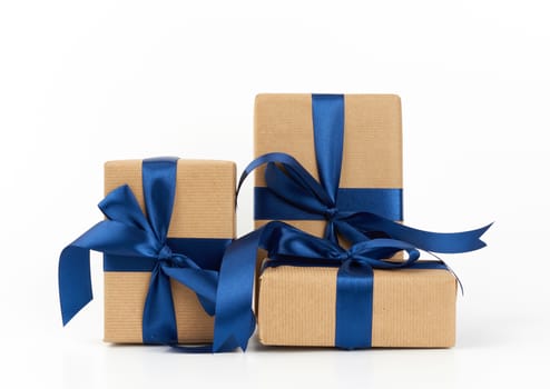 rectangle box wrapped in brown kraft paper and tied with a silk blue ribbon, gift isolated on a white background