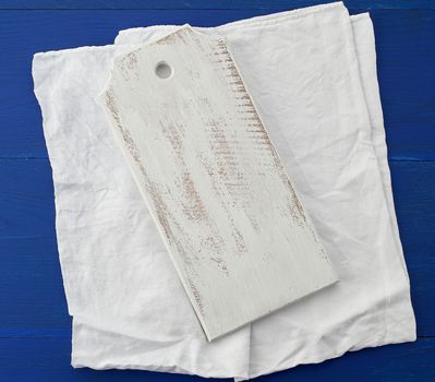 rectangular empty white kitchen cutting board and white textile towel on a blue wooden background from boards, top view