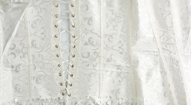 fragment of a white satin corset with lacing, back view, clothing item for brides