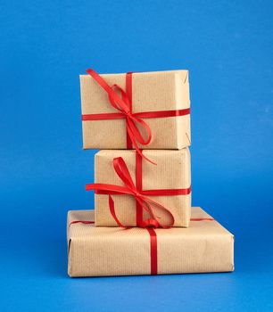 stack of boxes wrapped in brown paper and tied with a red bow, gifts on a blue background. Great design for any purposes. Holiday background. Valentine gift.