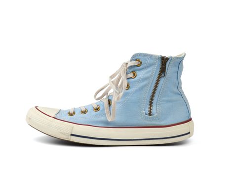 worn light blue sneaker with tied white laces and an iron zipper isolated on a white background, shoes stand sideways