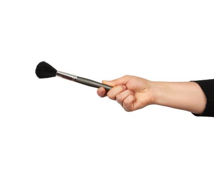 woman`s hand holds a gray brush for applying makeup on a white background