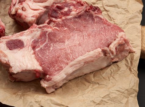 raw juicy pork slices of meat on the rib, food lies on brown parchment paper, top view