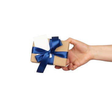 hand hold a wrapped gift in brown craft paper with tied silk blue bows, subject is isolated on a white background, concept of surprise and gift for the holiday