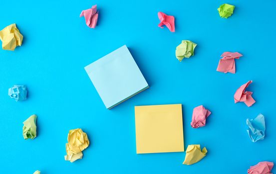 multicolored blank paper stickers of different colors on a blue background, copy space