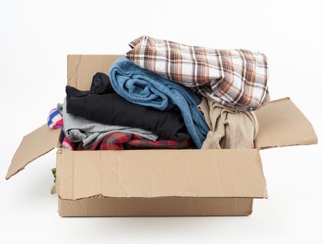 big brown cardboard box filled with various clothes on a white background, donation concept