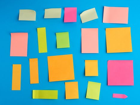 multicolored paper stickers of different shapes on a blue background, backdrop for the designer