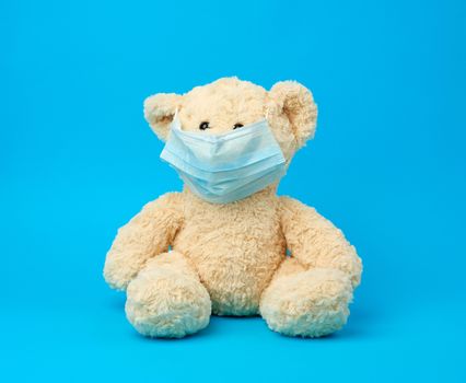 big teddy bear are sitting in medical masks on a blue background, concept of protection from respiratory disease, virus and individual respiratory protection