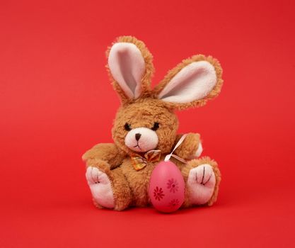 cute brown bunny and pink colored eggs on a red background, easter backdrop