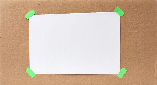blank paper ad with torn edges attached with a green velcro on a brown cardboard surface, backdrop for sales and messages, copy space