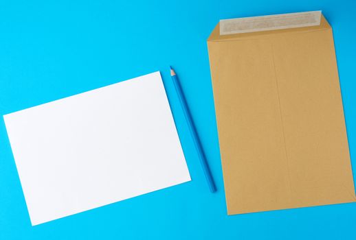 brown and white blank paper envelopes and wooden pencil on a blue background, flat lay