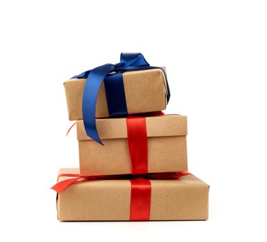 stack of gifts wrapped in brown kraft paper and tied with silk blue and red ribbon, boxes isolated on white background, element for designer
