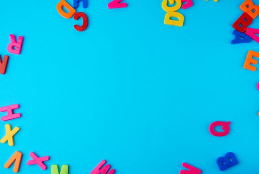 plastic multi-colored letters of the English alphabet on a blue-violet background, top view, back to school, copy space