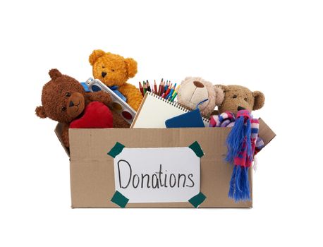 brown cardboard box filled with soft toys, school supplies on white background, concept of charity and help to needy children