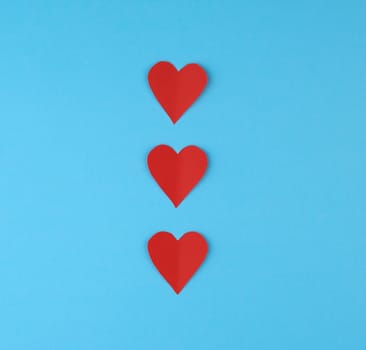 hearts cut out of red paper on a blue background, festive backdrop for Valentine's Day, copy space