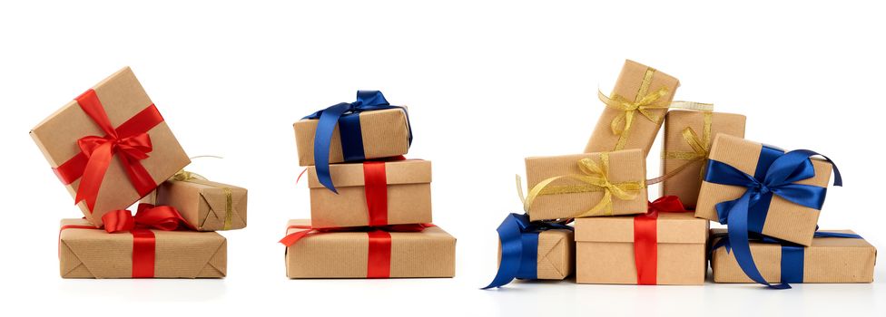 big stack of gifts wrapped in brown kraft paper and tied with silk blue and red ribbon, boxes isolated on white background, element for designer, set