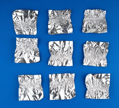 various crumpled foil used candy wrappers on a blue background, top view