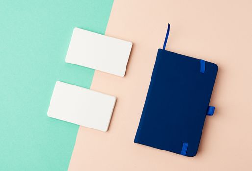 stack of rectangular white blank business cards and blue notebook on a green beige background, backdrop for the designer