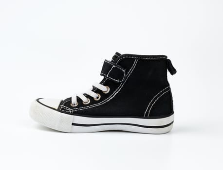 black textile sneaker with white tied shoelaces on a white background, shoes stand sideways