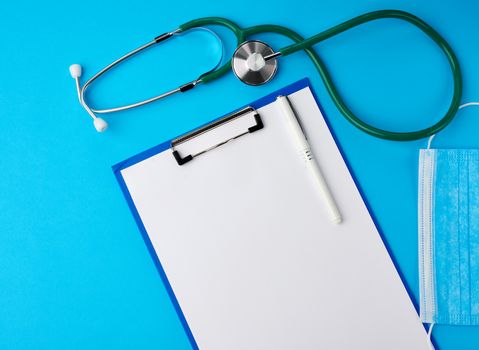 blank white sheet of paper and blue viscose medical mask for protection against the virus,  green stethoscope, cyan background