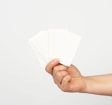 female hand holds a stack of white rectangular paper business cards on a white background, identity concept