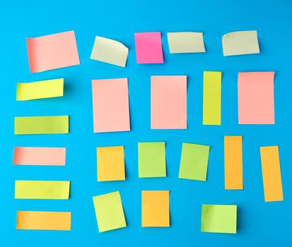 multicolored paper stickers of different shapes on a blue background, backdrop for the designer