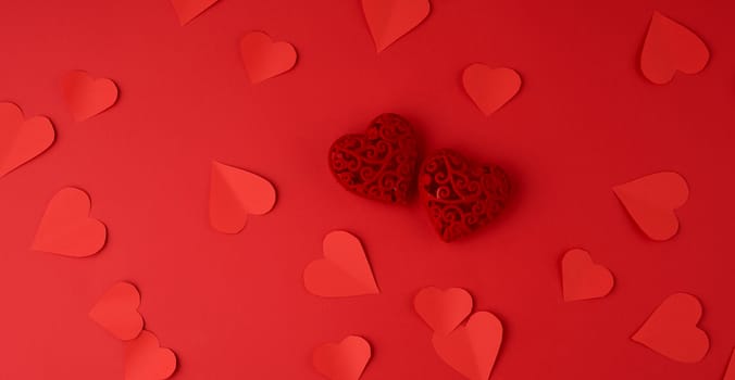 hearts cut out of red paper on a red background, festive backdrop for Valentine's Day, flat lay