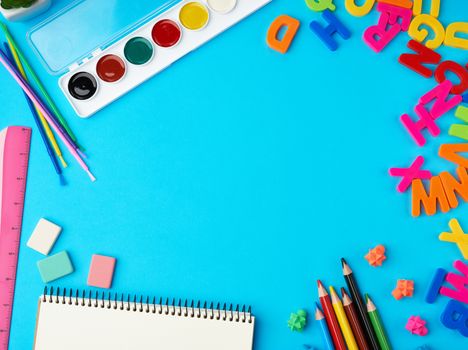 stationery school supplies for creativity and learning on a blue background, top view, empty space in the middle, flat lay