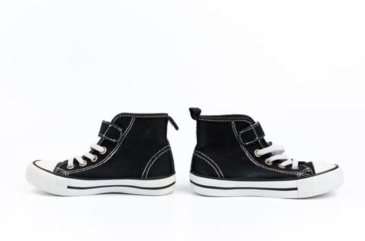 black textile sneakers with white tied shoelaces on a white background, pair shoes stand sideways