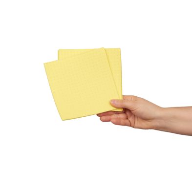 hand holds a yellow rag sponge for cleaning, part of the body is isolated on a white background