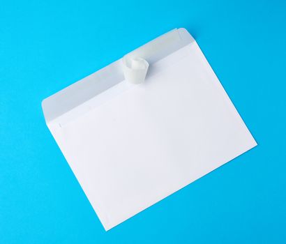 white rectangular blank paper envelope on a blue background, flat lay