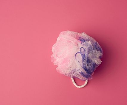 round synthetic washcloth on a pink background, top view