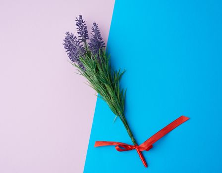 lavender bouquet and red ribbon on a color background, top view
