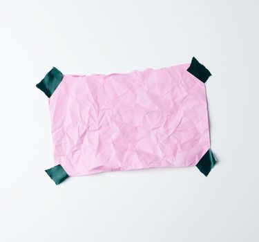 pink crumpled sheet of paper glued with adhesive tape on a white background, place for text