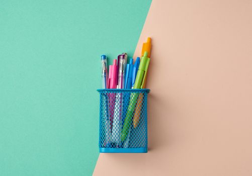 blue metal container for stationery, inside multi-colored plastic pens, top view