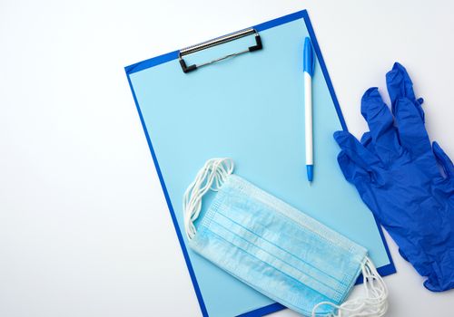  paper holder with a blank blue sheet, disposable blue medical mask on a white background, top view, flat lay