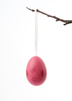 decorative plastic pink easter egg hanging on a branch, decor on a white background