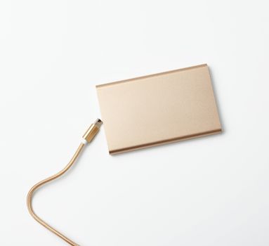 golden power bank and cord with a usb connector for recharging mobile devices on a white background, top view