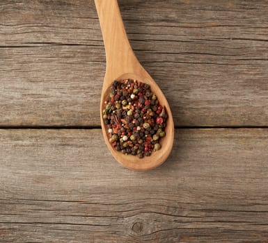 mix of dry balls of various peppers in a wooden spoon, top view