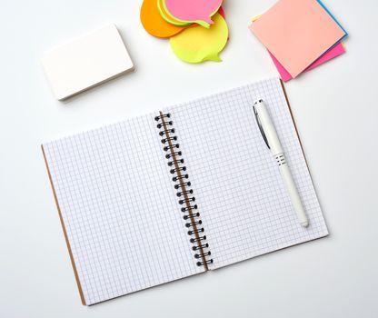 open notebook with blank white sheets, color stickers and rectangular business cards on a white background, top view, flat lay