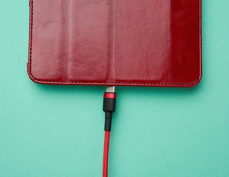 cable in red braid and electronic device on a green background, close up