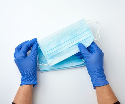 hands holds a medical face medical mask against viruses and bacteria on a white background, protective medical tool, top view