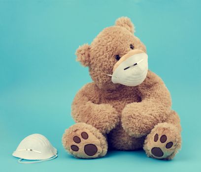 big teddy bear are sitting in medical masks on a blue background, concept of protection from respiratory disease, virus and individual respiratory protection