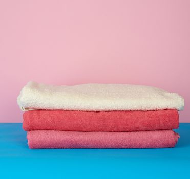 stack of pink folded towels on a blue background, set for a bath