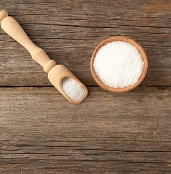 white coarse salt in a wooden spoon, gray table from old boards, top view