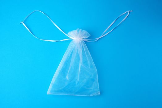 bag made of white transparent synthetic fabric for gifts and cosmetics on a blue background, top view